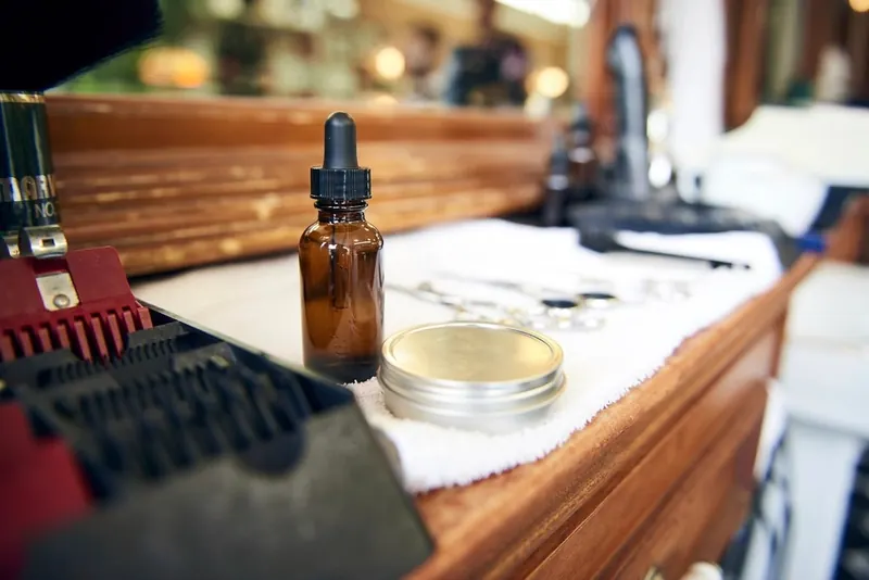 Beard oil and clipper guard on a barber's counter